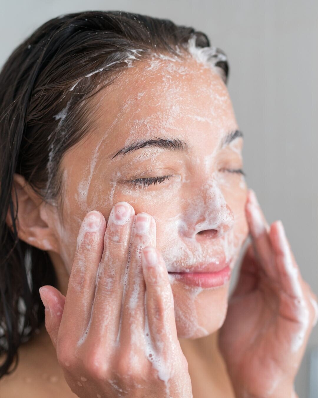 Mujer limpiando su rostro con espuma de jab&oacute;n